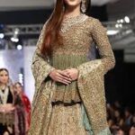 A 2025 Mughal-inspired bride wearing a richly embroidered lehenga with intricate gold zardozi work, traditional jewelry, and a regal dupatta, blending historical elegance with modern design.”