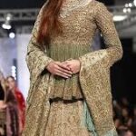 A 2025 Mughal-inspired bride wearing a richly embroidered lehenga with intricate gold zardozi work, traditional jewelry, and a regal dupatta, blending historical elegance with modern design.”