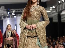 A 2025 Mughal-inspired bride wearing a richly embroidered lehenga with intricate gold zardozi work, traditional jewelry, and a regal dupatta, blending historical elegance with modern design.”