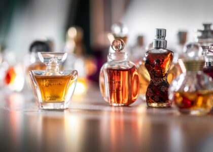 Collection of eco-friendly perfume bottles made from recycled materials, displayed on a natural wooden surface with greenery in the background, representing sustainable fragrance trends of 2025."