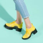 "Trendy 2025 footwear styles including chunky sneakers, futuristic heels, and eco-friendly shoes for men and women"