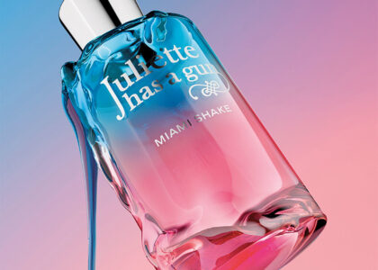 Bottle of Miami Shake perfume placed on a sunlit poolside table, with citrus fruits and palm leaves in the background.