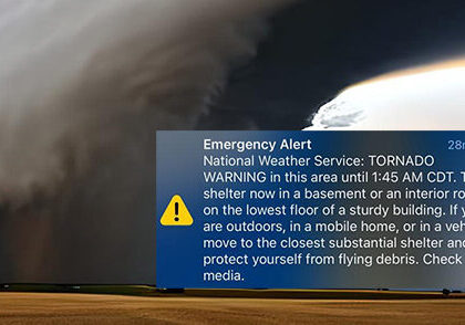 Dark storm clouds forming a funnel over a rural area during a tornado warning, capturing the urgency and danger of severe weather conditions.