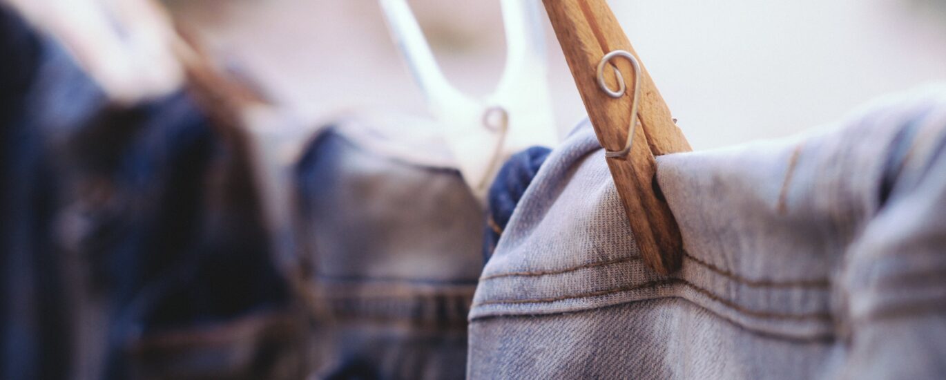 “Flat lay of the most common clothing in US: jeans, white t-shirt, hoodie, and sneakers on a wooden floor.”