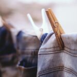 “Flat lay of the most common clothing in US: jeans, white t-shirt, hoodie, and sneakers on a wooden floor.”