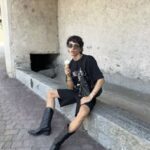 Fashionable woman wearing mini shorts and biker boots in an urban street-style outfit.