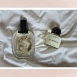 A bottle of clean, minimalistic perfume surrounded by soft white linen and summer light.