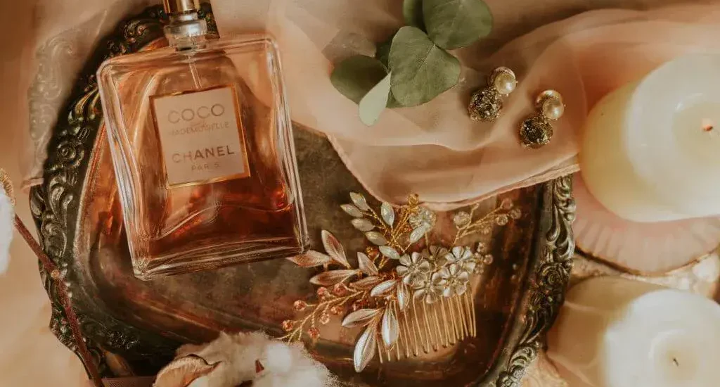 A curated flatlay of wedding day perfumes styled with pearls and silk gloves