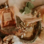 A curated flatlay of wedding day perfumes styled with pearls and silk gloves