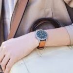 Solar-powered eco-friendly titanium wristwatch displayed on a minimalist wooden surface with natural lighting.