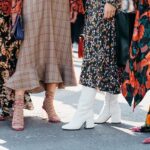 Model walking during Copenhagen Fashion Week's street style showcase wearing bold sneakers and layered fall outfit.