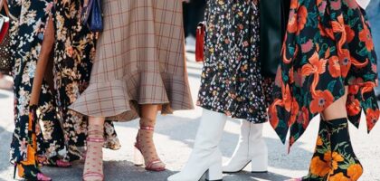 Model walking during Copenhagen Fashion Week's street style showcase wearing bold sneakers and layered fall outfit.