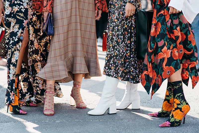 Model walking during Copenhagen Fashion Week's street style showcase wearing bold sneakers and layered fall outfit.
