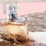 12 perfumes that smell like a beach vacation lined up on sandy beach towel